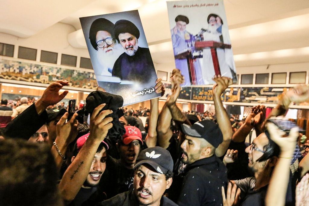 Para pendukung ulama Irak, Moqtada al-Sadr, mengangkat poster Sadr pada hari kedua aksi pendudukan gedung parlemen di Baghdad, Irak, Minggu (31/7/2022). 