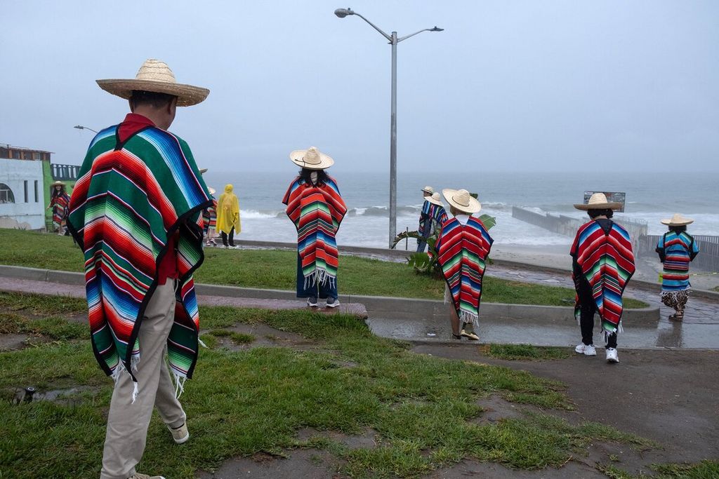 Wisatawan asal China berada di pantai dekat perbatasan Amerika Serikat-Meksiko saat badai tropis Hilary mendekat di Playas de Tijuana, Negara Bagian Baja California, Meksiko, Minggu (20/8/2023). 