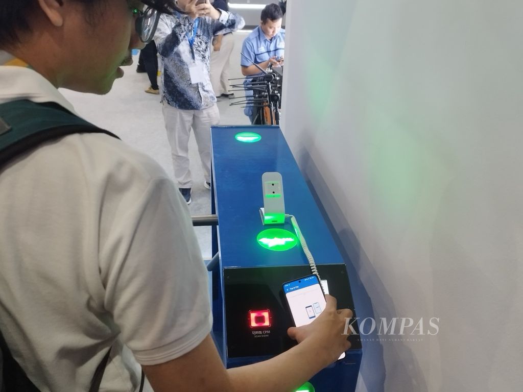 Seorang pengunjung pameran Festival Ekonomi Keuangan Digital Indonesia (FEKDI) 2024 tengah menjajal pemindaian QRIS Tap pada pintu masuk transportasi umum di Jakarta Convention Center, Jakarta, Jumat (2/8/2024).