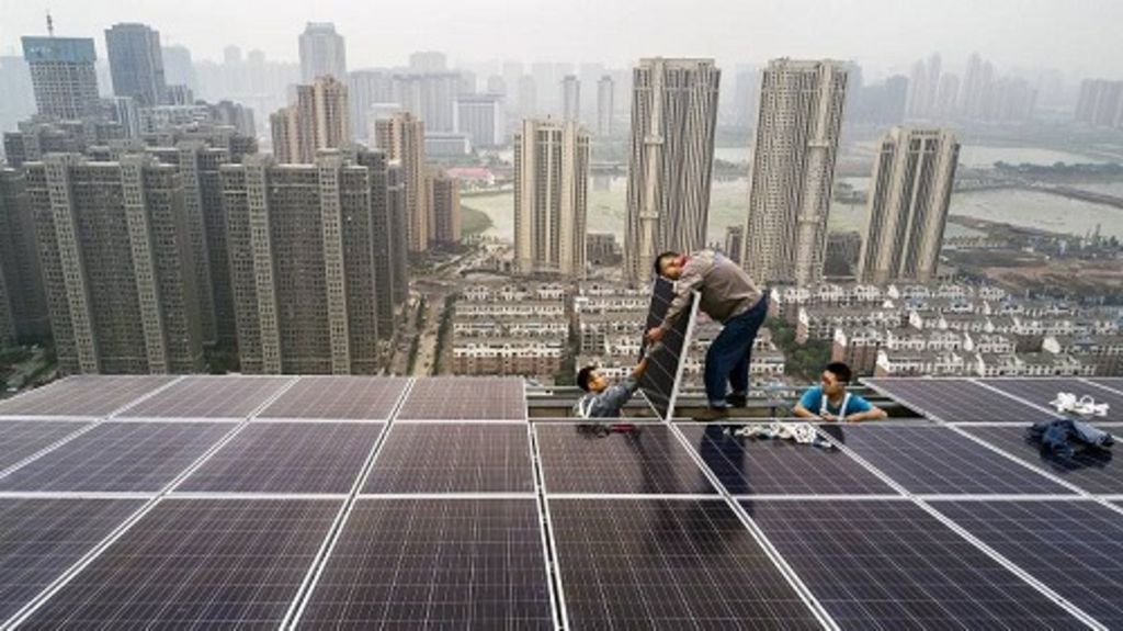 Pekerja Wuhan Guangsheng Photovoltaic mengerjakan proyek panel surya di atap sebuah gedung bertingkat 47 di Wuhan, China, Senin (15/7). China mengonsumsi lebih banyak listrik daripada negara lain, tetapi juga merupakan produsen energi surya terbesar di dunia. 