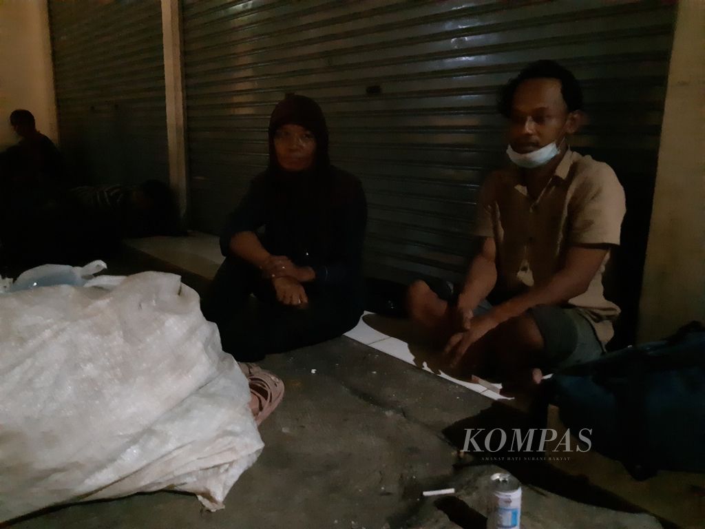 Pasangan suami istri Andry (38) dan Iis (48) yang bekerja sebagai pemulung tengah beristirahat di sebuah ruko di dekat Pasar Palmerah, Jakarta Barat, pada Jumat (17/3/2023) malam.