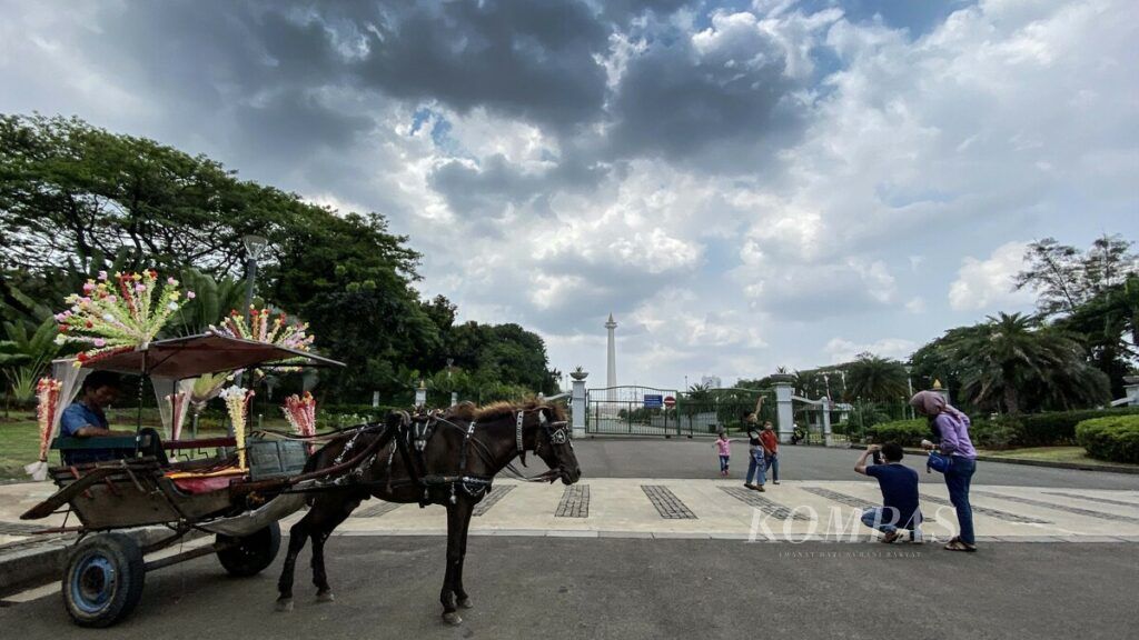 Warga berfoto di luar pagar Kompleks Monumen Nasional (Monas) Jakarta, Kamis (20/8/2020). Hingga kini Pemerintah Provinsi DKI Jakarta masih menutup kawasan Monas guna mencegah penyebaran COVID-19.