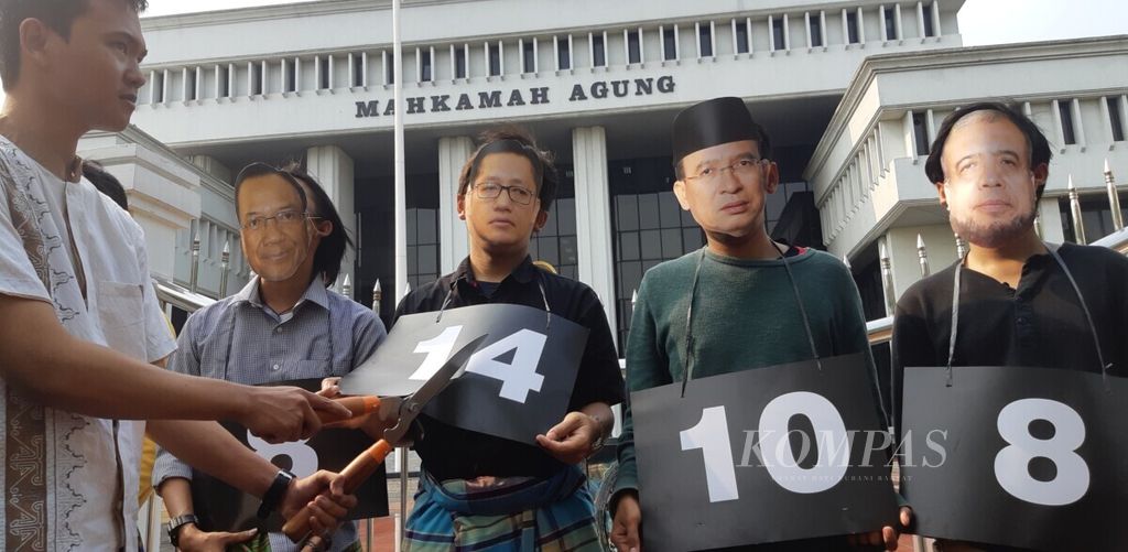 Para aktivis Indonesia Corruption Watch mengenakan topeng berfoto wajah narapidana korupsi dengan papan angka vonis hukuman penjara mereka. Aktivis lain yang memegang gunting rumput memangkas papan kertas itu digambarkan sebagai hakim yang memutus kabul pengajuan peninjauan kembali para narapidana tersebut.