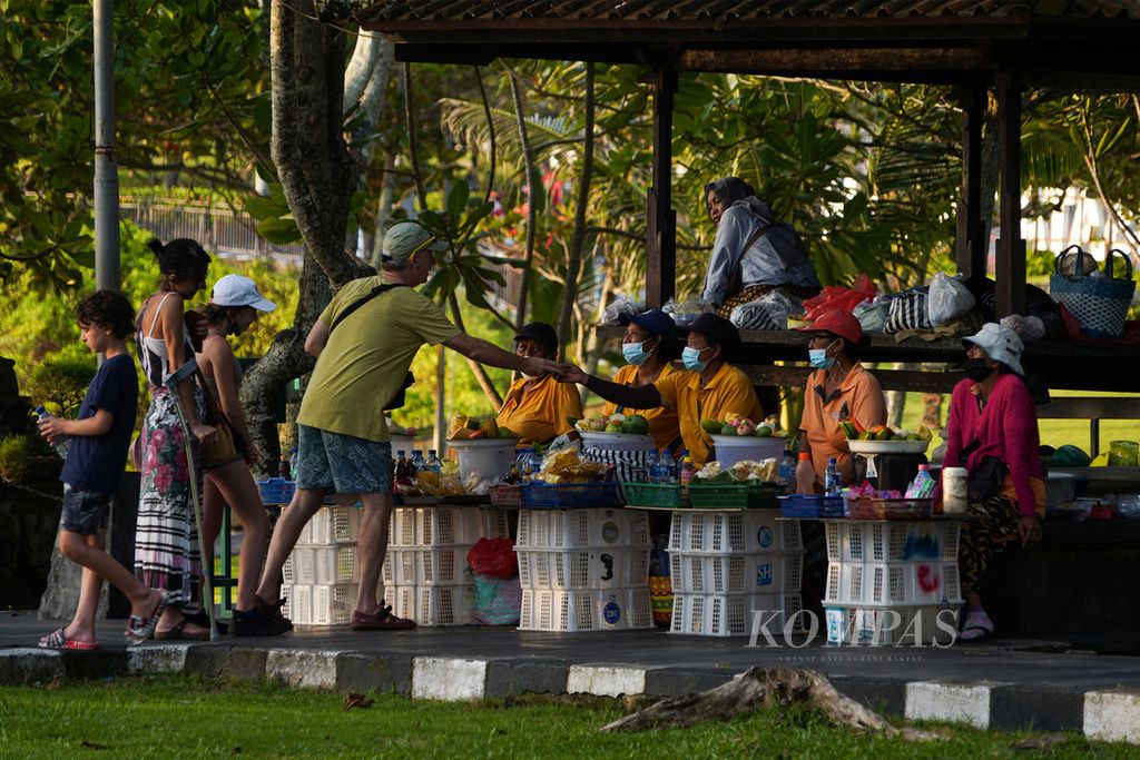 Wisatawan mancanegara berbelanja makanan yang dijual pedagang di kawasan Pura Tanah Lot, Kecamatan Kediri, Kabupaten Tabanan, Bali, Jumat (15/10/2021). Wisatawan mancanegara yang ada di Bali merupakan wisatawan yang sudah lama ada di Bali atau masuk ke Bali lewat Jakarta atau Manado. 