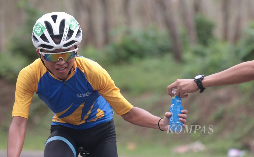Pebalap meminta air isotonik saat melintasi kawasan Waluran, Sukabumi, Jawa Barat, pada etape pertama Cycling de Jabar 2023, Sabtu (8/7/2023). Etape pertama menempuh jarak 199,7 kilometer yang dimulai dari Pantai Palangpang, Sukabumi, dan finis di Rancabuaya, Garut. 