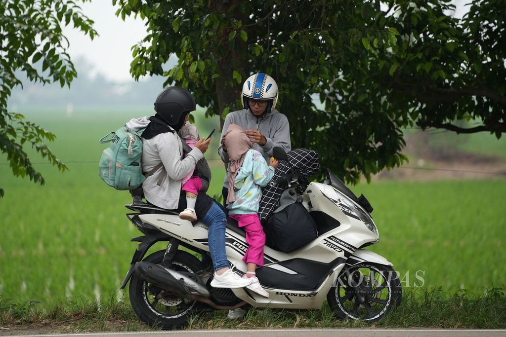 Pemudik sepeda motor beristirahat di pinggir sawah di Jalan Lingkar Tanjungpura, Karawang, Jawa Barat, Sabtu (6/4/2024).  Survei Kementerian Perhubungan menunjukkan, minat masyarakat untuk menggunakan sepeda motor saat mudik tahun ini sebesar 16,07 persen atau 31,12 juta orang.