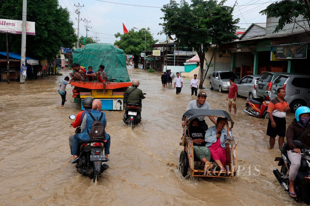 Vehicles belonging to residents who are passing through the flooded Jalan Semarang-Grobogan access road in Gubug Sub-district, Grobogan Regency, Central Java, on Tuesday (6/2/2024). The flood came from the overflow of the Tuntang River that occurred since early morning, causing the road to be cut off, the river embankment to collapse, and inundating residential areas and public facilities. Until now, some traffic has been redirected to several alternative routes.