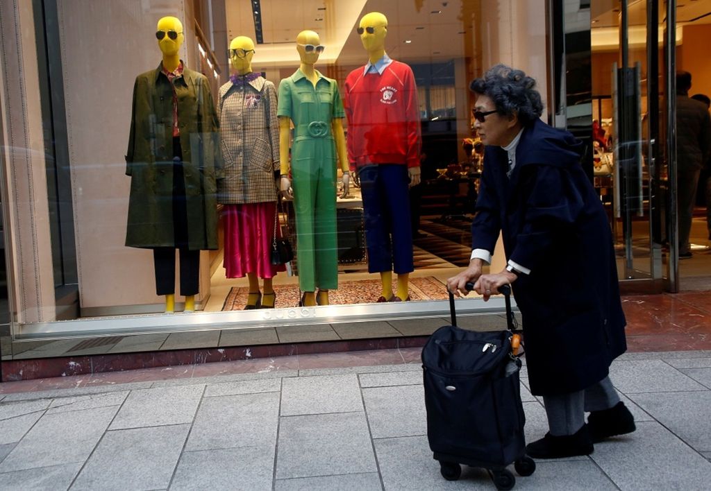 Seorang perempuan berjalan melewati sebuah toko di kawasan pusat belanja di Tokyo, Jepang, Rabu (7/3). (REUTERS/Kim Kyung-Hoon)