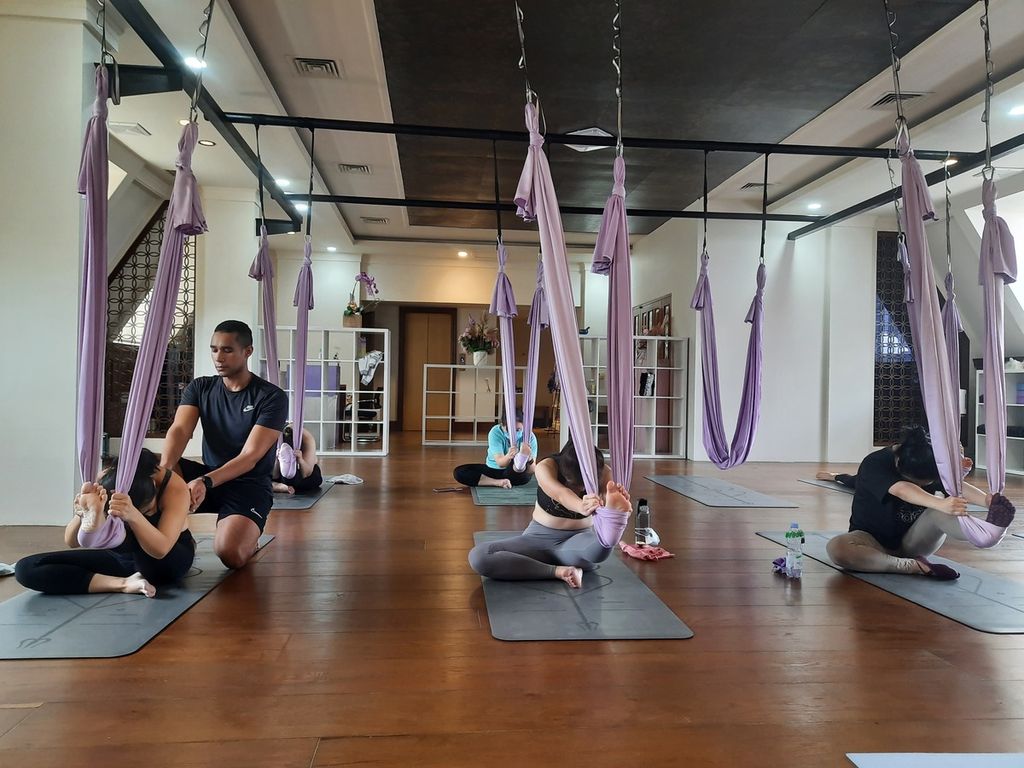Instruktur yoga Mohamed Dawoud (28) asal Mesir sedang memperbaiki postur tubuh peserta yoga kelas <i>aerial yin</i> di studio Vibe Yoga, Jakarta, Minggu (20/11/2022). Vibe Yoga menawarkan sejumlah kelas dengan harga yang bervariasi, baik privat maupun kelompok.