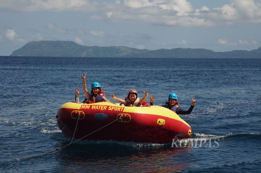 Wisatawan asal China menikmati wahana <i>donut boat </i>di perairan Pulau Gangga, Minahasa Utara, Sulawesi Utara, Jumat (31/1/2020). Rombongan itu adalah yang terakhir mengunjungi Pulau Gangga sebelum penerbangan dari China ditutup untuk sementara.