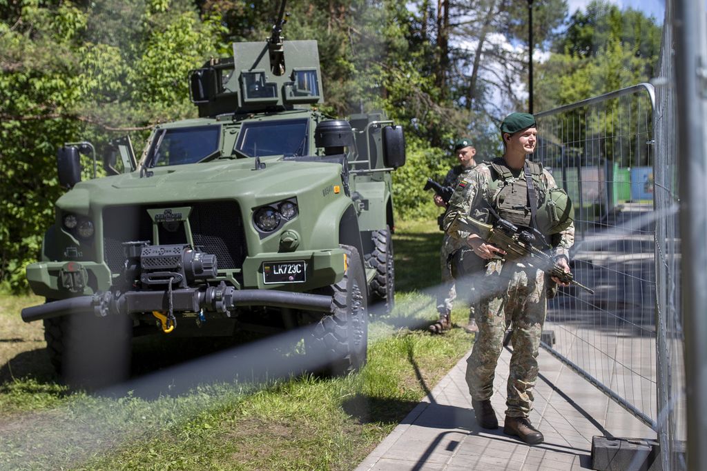 Beberapa anggota militer Lithuania berjaga di balik pagar yang mengelilingi lokasi penyelenggaraan KTT NATO di Ibu Kota Lithuania, Vilnius, Minggu (9/7/2023). Dua hal yang diduga akan menjadi diskusi hangat selama KTT, yaitu aksesi keanggotaan Swedia dan pengiriman bom tandan untuk Ukraina. 