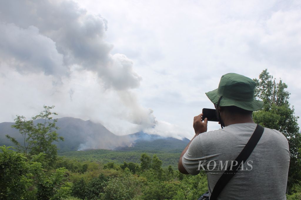 Seorang jurnalis memotret erupsi Gunung Lewotobi Laki-laki di Kabupaten Flores Timur, Nusa Tenggara Timur pada Selasa (16/1/2024). Tampak awan panas dan lava meluncur ke sisi timur laut gunung.