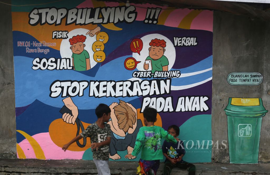 Anak-anak bermain dengan latar mural untuk mencegah perundungan dan kekerasan terhadap anak di perkampungan RW 01 Rawa Bunga, Jatinegara, Jakarta Timur, Kamis (16/12/2021). 