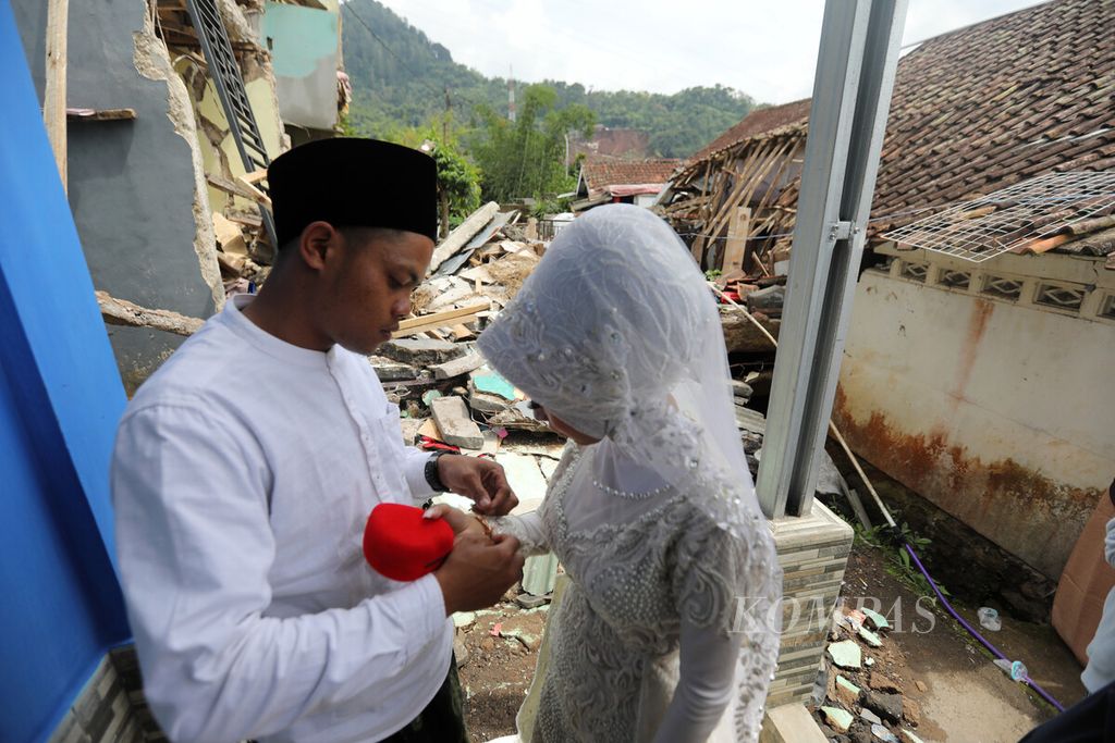Muhammad Nurdin mengenakan mas kawin kepada istrinya, Nida Khovia Syukur, setelah melaksanakan prosesi akad nikah di Kecamatan Cugenang, Kabupaten Cianjur, Jawa Barat, Desember 2022. Desa tempat mereka tinggal dihantam gempa. 