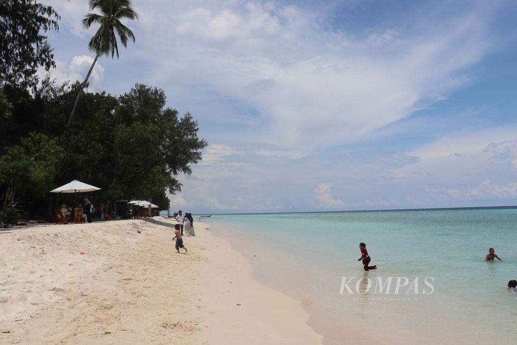 Pengunjung bermain-main di Pantai Tanjung Waka, Desa Fatkauyon, Kecamatan Sulabesi Timur, Kepulauan Sula, Maluku Utara, Minggu (27/3/2022). Pantai dengan pasir putih dan laut jernih itu menjadi tempat wisata unggulan di Kepulauan Sula.