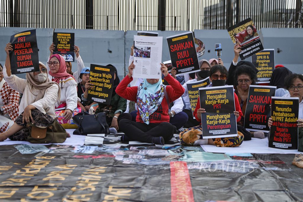 Peserta membawa poster tuntutan dalam aksi menuntut pengesahan Rancangan Undang-Undang Perlindungan Pekerja Rumah Tangga (RUU PPRT) di depan Kompleks Parlemen, Jakarta, Kamis (21/3/2024). 