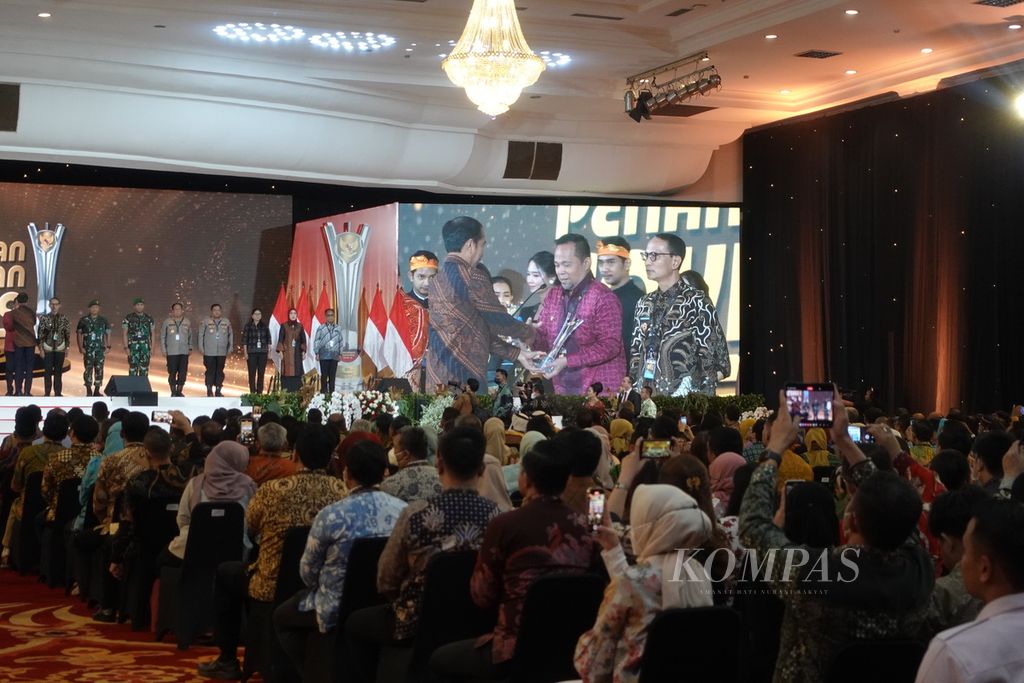 Presiden Joko Widodo saat menyerahkan penghargaan bagi pihak-pihak yang berkontribusi dalam pengendalian Covid-19 pada acara penghargaan penanganan Covid-19 yang digelar di Gedung Dhanapala Kementerian Keuangan, Jakarta, Senin (20/3/2023).