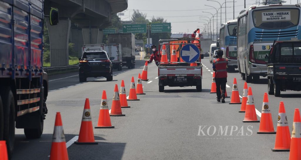 Petugas menurunkan rambu kerucut untuk membagi jalur kendaraan saat uji coba penerapan rekayasa lalu lintas ganjil genap di Jalan Tol Jakarta-Cikampek di Km 47 Karawang, Jawa Barat, Senin (25/4/2022). 