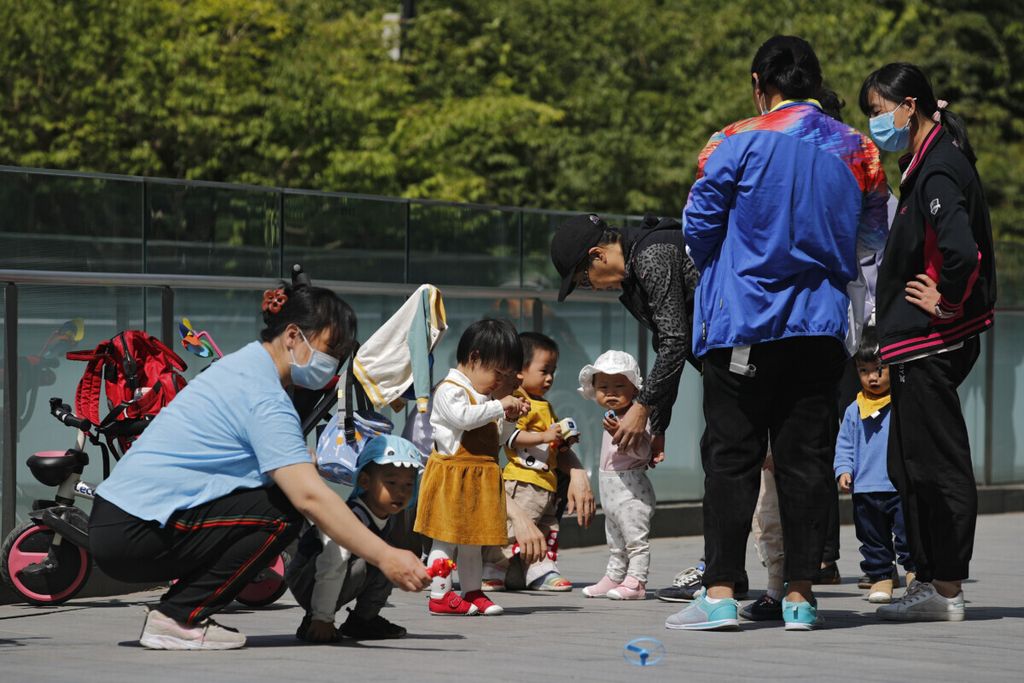 Warga membawa anak-anak mereka bermain di dekat kawasan komersial di Beijing, China, 10 Mei 2021. Partai Komunis China menghapus batasan yang memperbolehkan pasangan suami istri memiliki tiga anak untuk mendongkrak penurunan angka kelahiran di negara itu. 