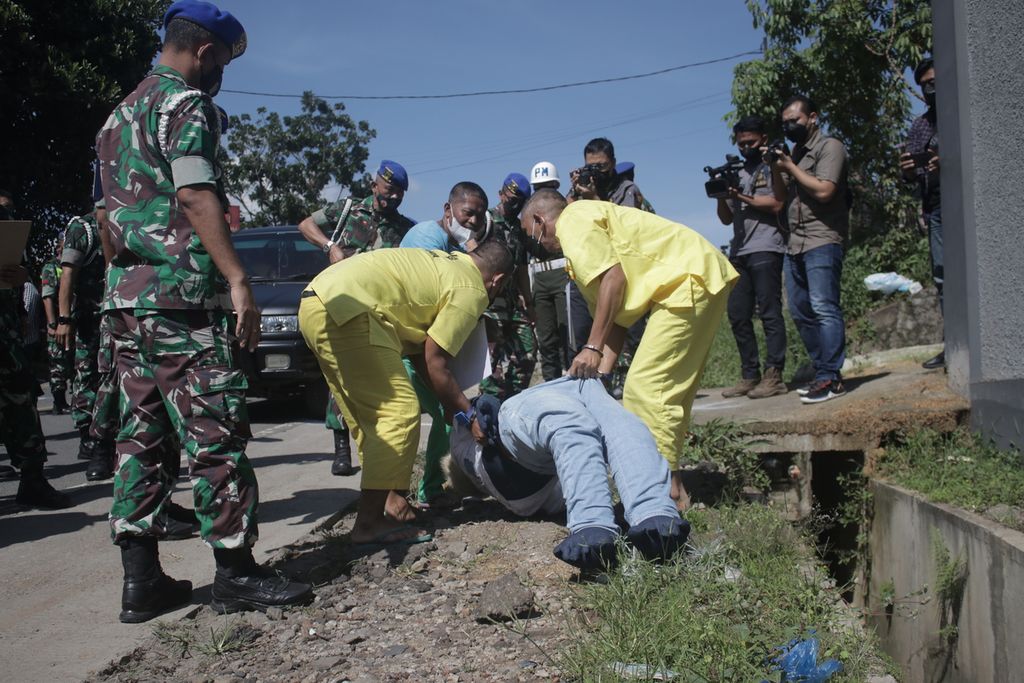 Dua tersangka mengangkut boneka model korban dalam rekonstruksi adegan kecelakaan yang melibatkan tiga anggota TNI di Jalan Nasional III, Desa Ciaro, Kecamatan Nagreg, Kabupaten Bandung, Jawa Barat, Senin (3/1/2022). 