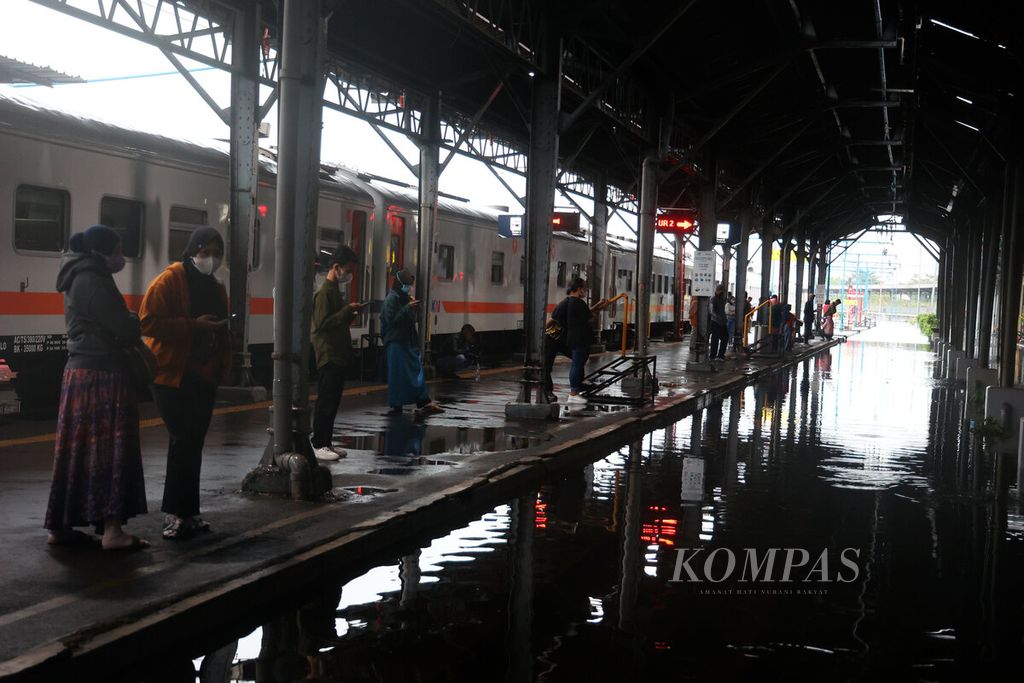 Penumpang turun dari kereta api setelah perjalanan mereka ditunda sementara menunggu surutnya banjir yang menggenangi sejumlah titik rel di Stasiun Tawang, Kota Semarang, Jawa Tengah, Sabtu (31/12/2022). 