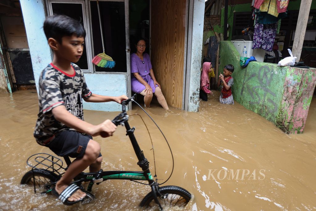 Seorang anak bermain sepeda di tengah genangan banjir di Kelurahan Kampung Melayu, Kecamatan Jatinegara, Jakarta Timur, Kamis (30/11/2023). 