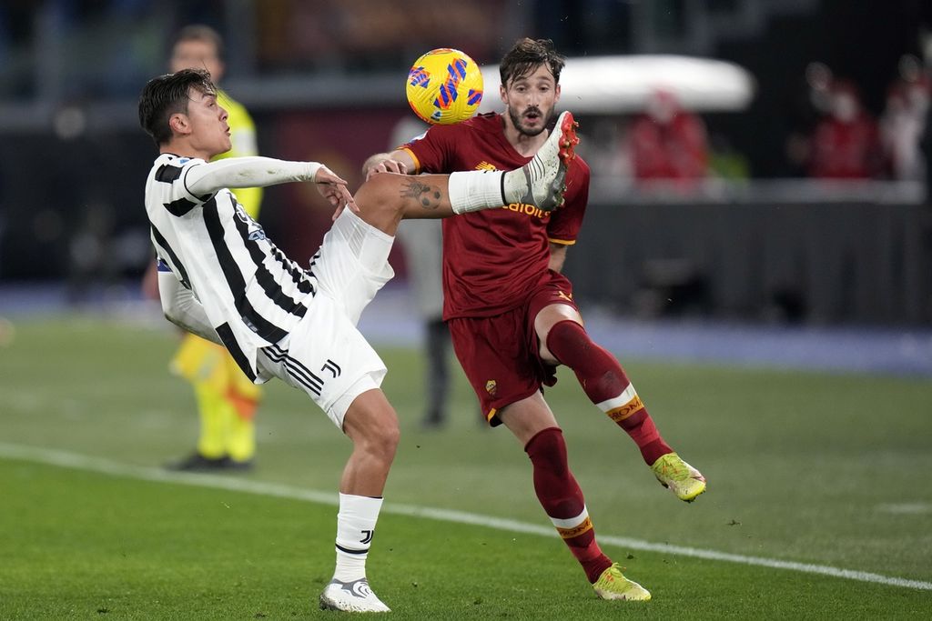 Penyerang Juventus, Paulo Dybala (kiri), mengontrol bola saat dibayangi bek AS Roma, Matias Vina, dalam lanjutan Liga Italia di Stadion Olimpico, Roma, Italia, Senin (10/1/2022) dini hari WIB. (AP Photo/Alessandra Tarantino)