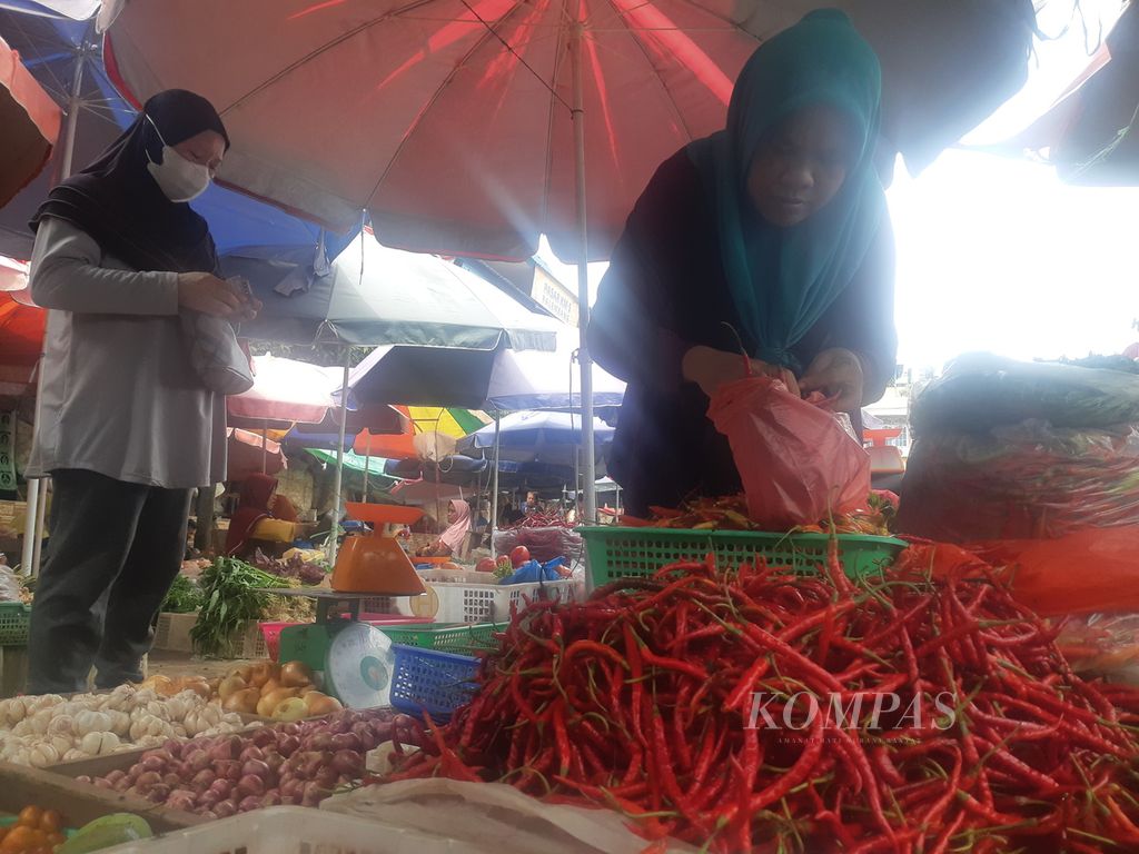 Seorang pedagang di Pasar KM 5 Palembang, Sumatera Selatan, sedang melayani pembeli cabai, Rabu (13/7/2022). Harga komoditas di Palembang berangsur turun dibandingkan dengan sebelum Idul Adha. Pedagang pun mengalami penurunan omzet lantaran berkurangnya daya beli masyarakat. 