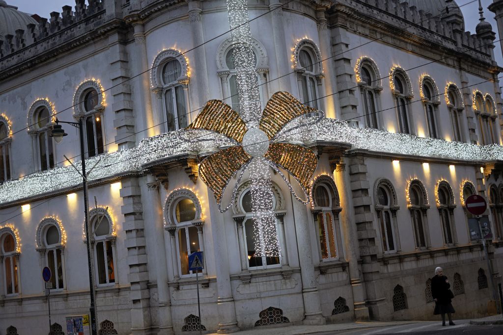 Seorang warga berjalan di samping sebuah gedung yang berhiaskan lampu-lampu Natal di Lisabon, Portugal, 26 November 2023. 