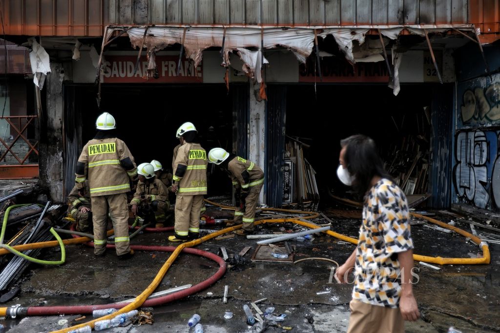 A resident walks past firefighters who are preparing hoses to conduct cooling operations on Mampang Prapatan Street in South Jakarta on Friday (19/4/2024).