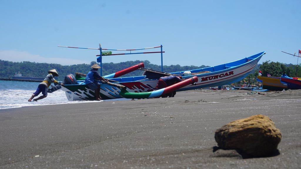 Sejumlah nelayan gotong royong mendorong perahu ke daratan di Pantai Teluk Penyu Cilacap, Jawa Tengah, Kamis (16/1/2020). Ombak tinggi dan angin kencang diwaspadai para nelayan saat melaut.