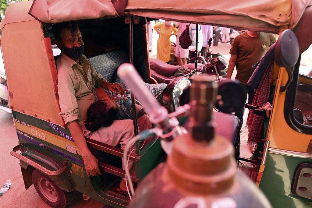 Seorang pasien bernafas dengan bantuan oksigen yang disediakan oleh Gurdwara, tempat ibadah untuk Sikh, di dalam becak mobil yang diparkir di pinggir jalan di Ghaziabad, India, di tengah pandemi Covid-19, Senin (26/4/2021).
