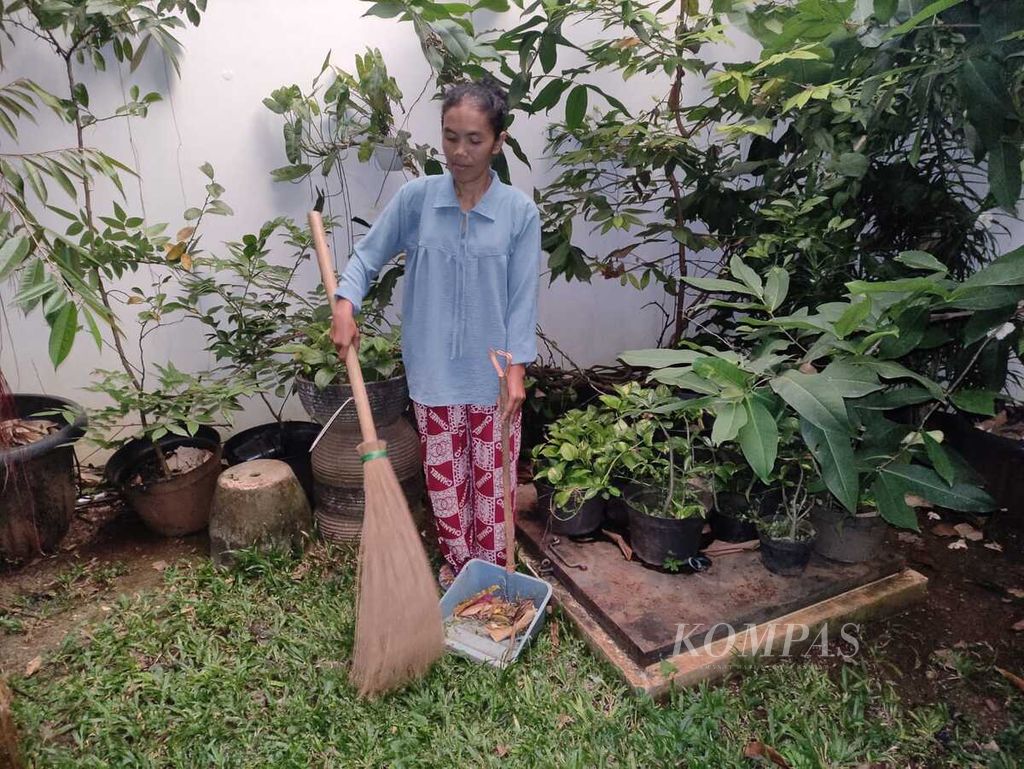 Yanti Rosmiati (41) menyapu halaman rumah di Jakarta, Jumat (14/4/2023). Warga Bogor, Jawa Barat, itu menjadi pekerja infal karena upahnya lebih tinggi dibandingkan hari biasa. Ia rela mengorbankan waktu berkumpul dengan keluarga saat Lebaran.