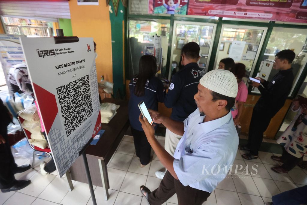 Warga menggunakan QRIS untuk membayar pembelian beras saat acara operasi pasar sekaligus sosialisasi penggunaan QRIS di Pasar Beringharjo, Yogyakarta, Kamis (9/2/2023). 
