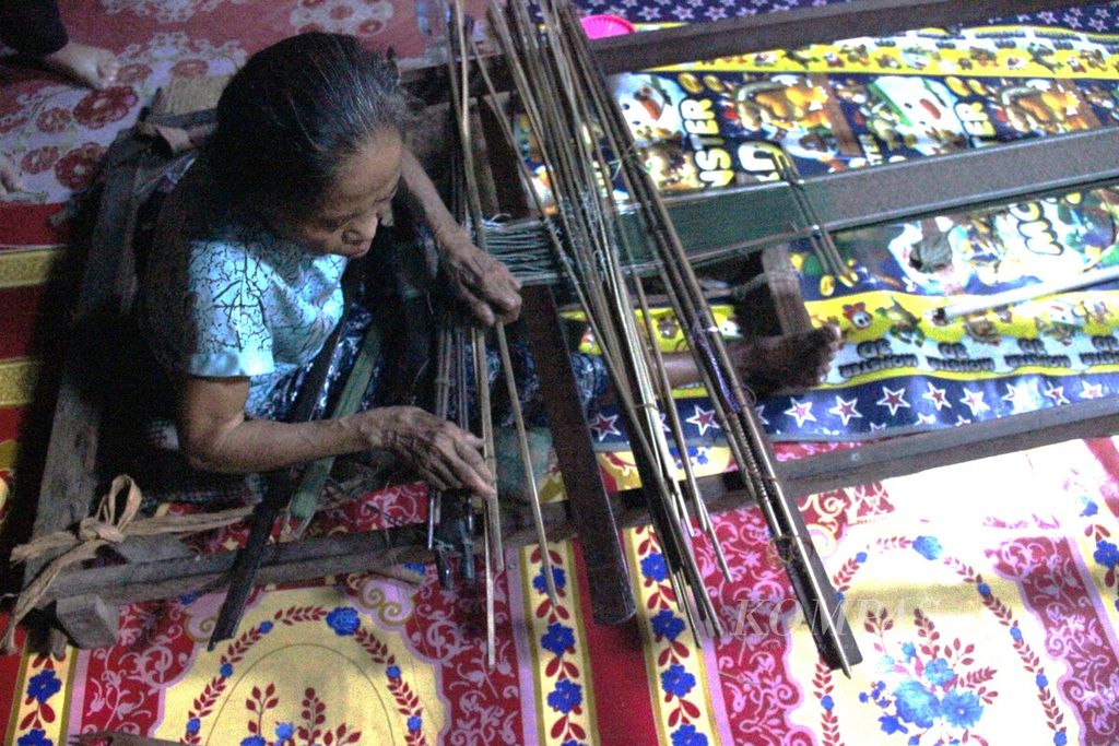Salah satu penenun di Rumah Panjang Dayak Iban Sungai Utik di Desa Batu Lintang, Kecamatan Embaloh Hulu, Kabupaten Kapuas Hulu, Kalimantan Barat, sedang menenun, Senin (26/6/2023).