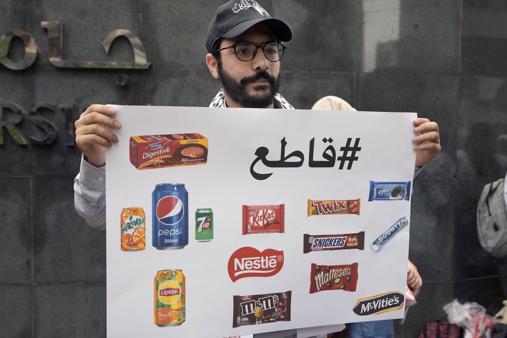 Seorang mahasiswa memegang pkalat bertuliskan daftar perusahaan yang diboikot karena mendukung Israel saat demonstrasi di Universitas Beirut Arab di Beirut, Lebanon, Selasa (30/4/2024).