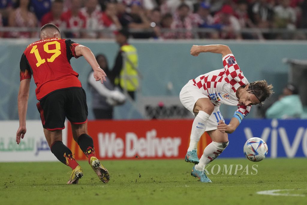 Pemain Kroasia, Luca Modric (kanan), berebut bola dengan pemain Belgia, Leander Dendoncker, dalam pertandingan penyisihan Grup F Piala Dunia 2022 di Stadion Ahmad Bin Ali, Qatar, Kamis (01/12/2022). Pertandingan berakhir imbang 0-0. 