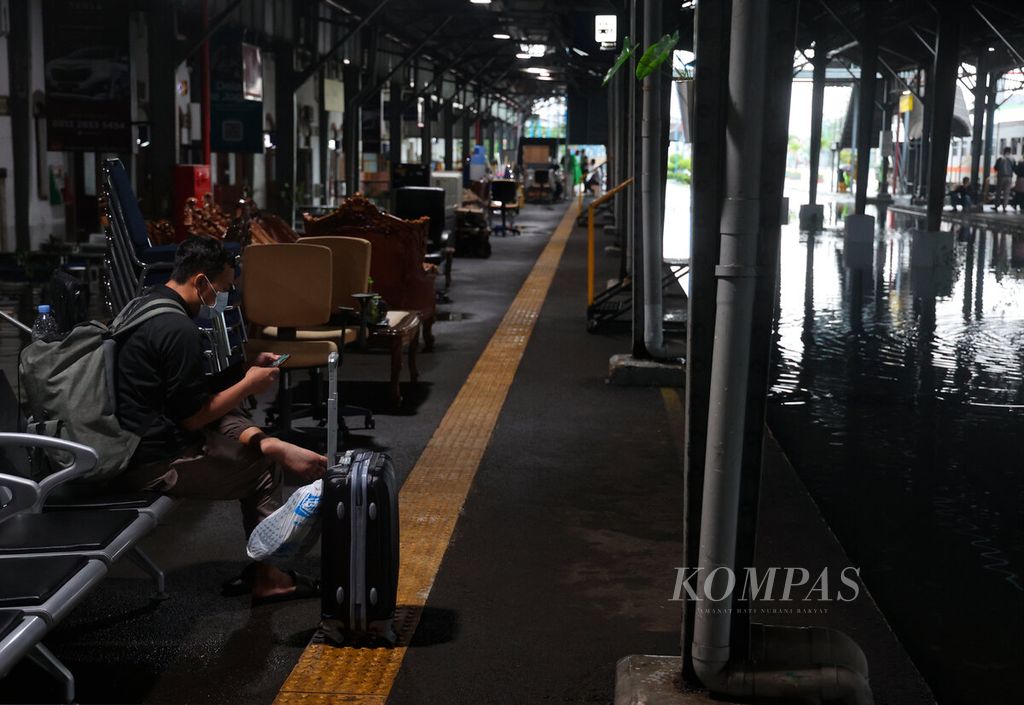 Salah satu penumpang terpaksa menunggu keberangkatan kereta api yang ditunda hingga banjir surut di Stasiun Tawang, Kota Semarang, Jawa Tengah, Sabtu (31/12/2022).