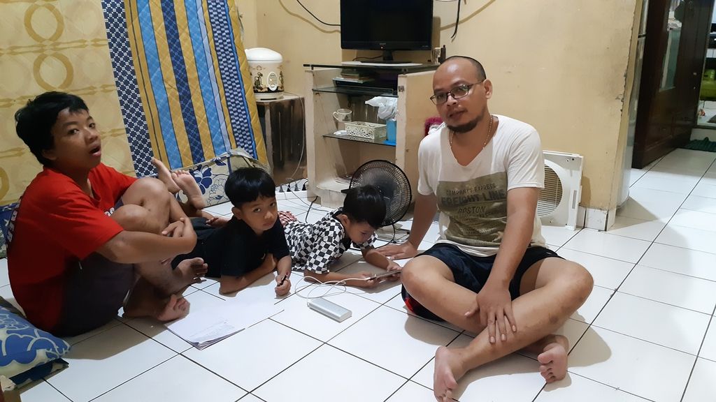 Juliadri (35), warga RT 005 RW 001, Kelurahan Kelurahan Tanjung Duren Selatan, Grogol Petamburan, Jakarta Barat, menemani anak-anaknya, Zaki (5), Rafa (7), dan Zulfi (12), di rumah belajar dan mengerjakan tugas-tugas harian sekolah, Kamis (16/4/2020).