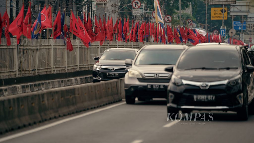 Warga melintasi bendera partai politik Partai Demokrasi Indonesia Perjuangan (PDI-P) dan Partai Nasdem di Jalan Tambak, Jakarta Pusat, Minggu (19/6/2022). 