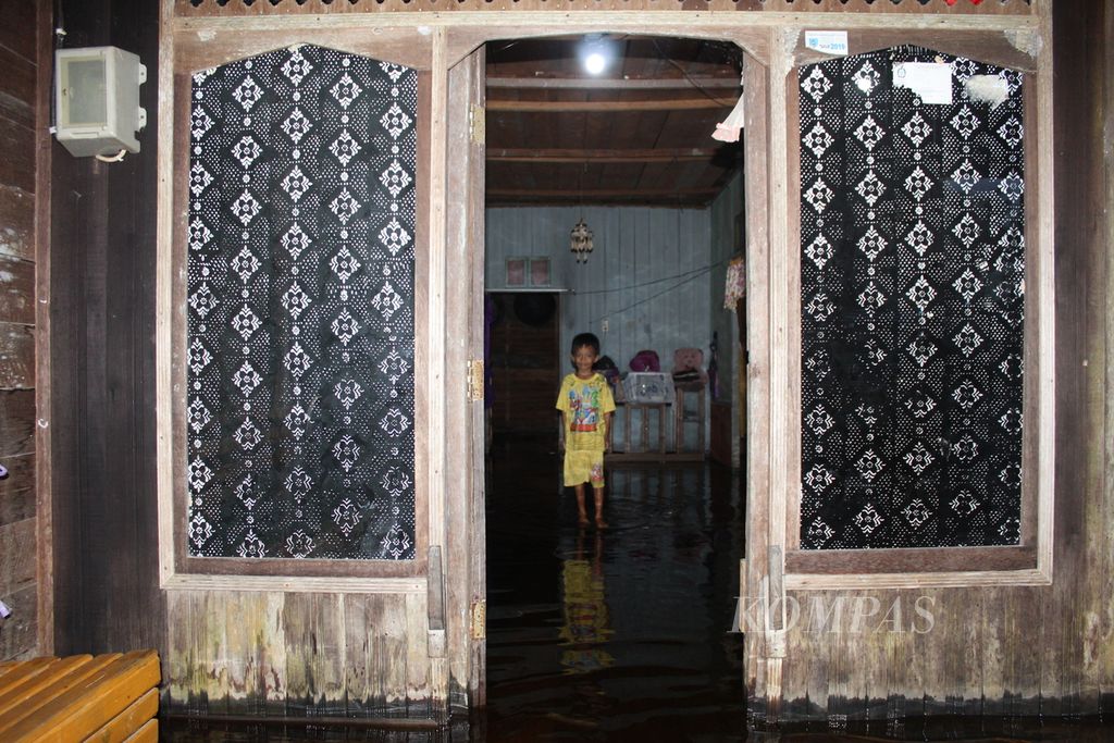 Seorang anak menunggu banjir surut di rumahnya di Desa Desa Dusun Jutuh, Kabupaten Barito Selatan, Kalimantan Tengah pada Rabu (24/1/2024). Ratusan warga mengungsi keluar desa karena sudah tiga hari banjir tak kunjung surut di wilayah itu.