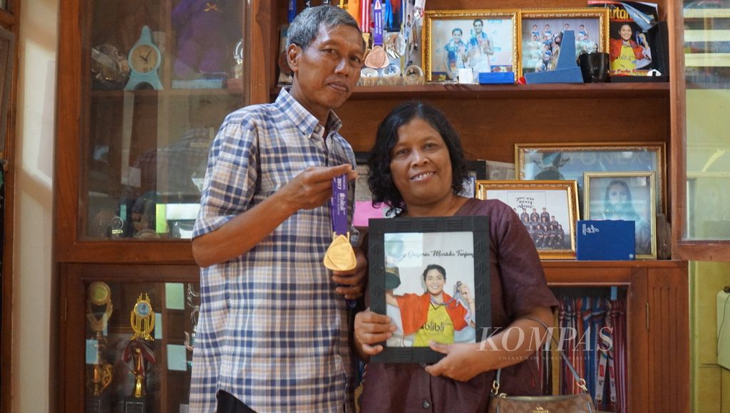 Gregorius Maryanto (kiri) dan Fransiska Romana (kanan) berfoto dengan medali dan potret putrinya, Gregoria Mariska Tunjung Cahyaningsih, di kediaman mereka, Desa Bulusulur, Kecamatan Wonogiri, Kabupaten Wonogiri, Jawa Tengah, Selasa (6/8/2024). Sang putri menjadi peraih medali perunggu Olimpiade Paris 2024 dari cabang olahraga bulu tangkis. 