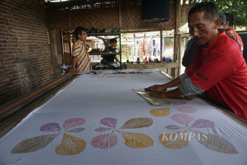 Perajin batik sedang menyelesaikan proses pembuatan batik dengan teknik lampas <i>godhong</i> atau menggosok daun di Rumah Batik R di Sokaraja, Banyumas, Jawa Tengah, Kamis (27/10/2022).