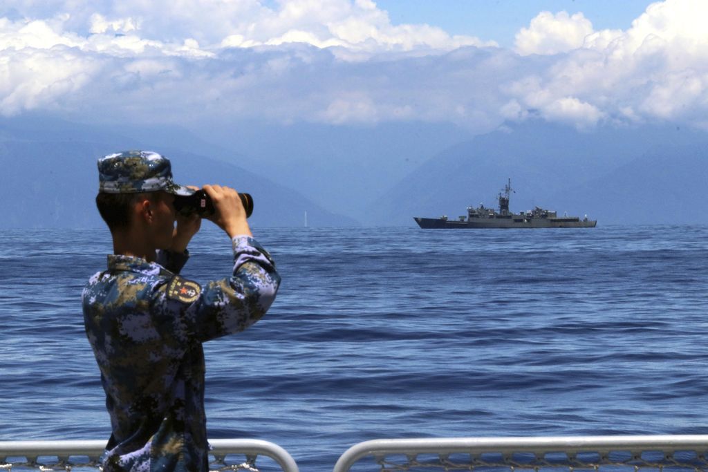 Seorang tentara China menggunakan teropongnya dalam sebuah latihan militer, sementara sebuah kapal fregat Taiwan, Lan Yang, terlihat berlayar tak jauh darinya, 5 Agustus 2022. 