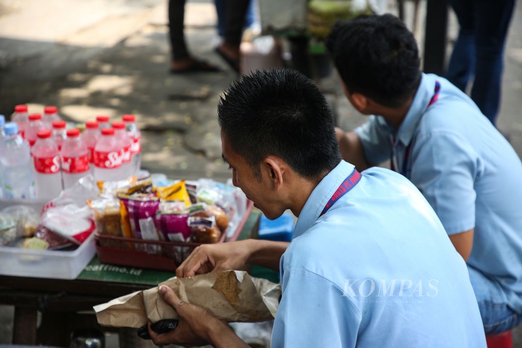 Buruh menikmati makan siang dari pedagang yang<i> mangkal</i> di luar area pabrik di kawasan Karawaci, Kota Tangerang, Banten, Rabu (22/11/2023). 