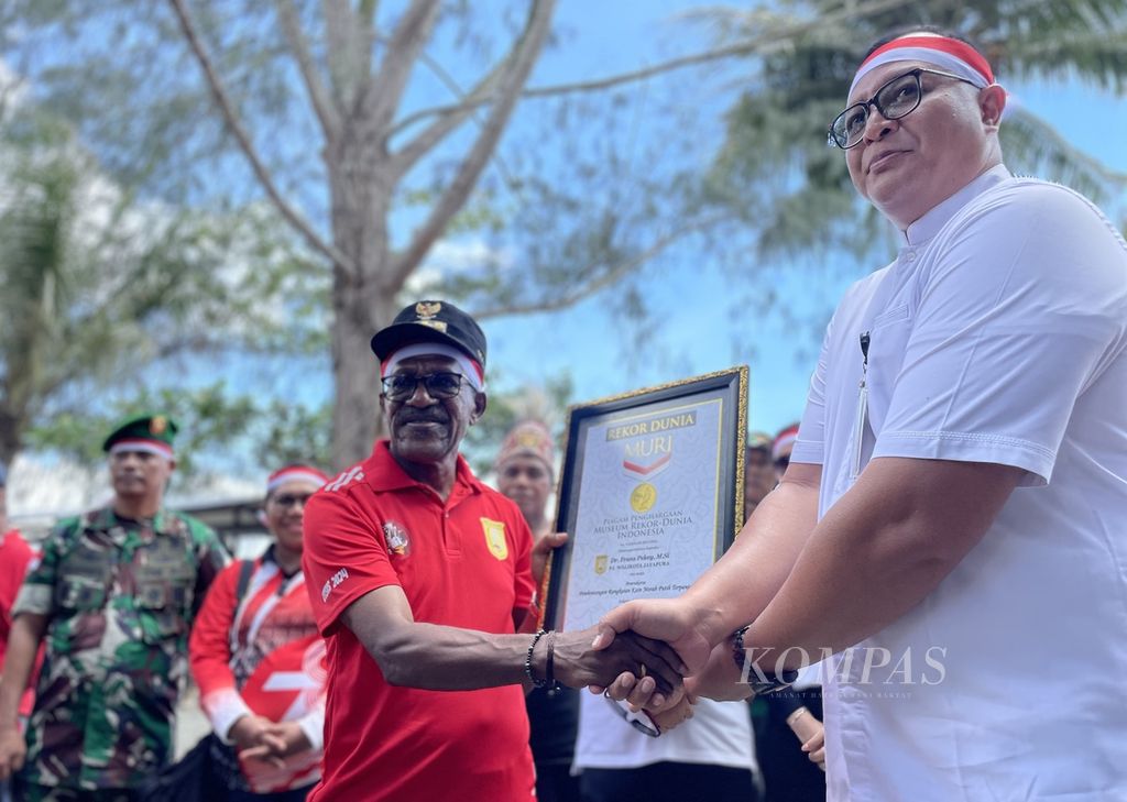 Penjabat Wali Kota Jayapura Frans Pekey (baju merah) menerima piagam rekor Muri pengibaran bendera Merah Putih terpanjang di Kota Jayapura, Papua, Rabu (1/5/2024).