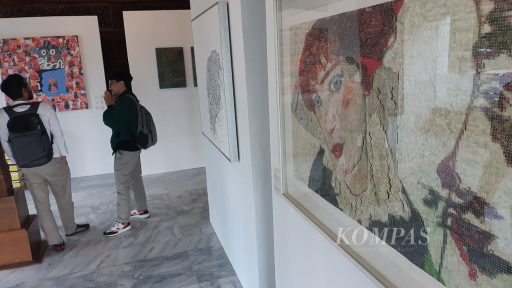 Senin (23/01/2023), seorang pengunjung menikmati karya seni dalam pameran seni bertajuk Mom3nt yang digelar pada 23 Januari-23 Februari 2023 di lobi Hotel Rayz Universitas Muhammadiyah Malang. Tampak lukisan dengan pendekatan <i>pictorial pixel</i> turut dipamerkan.