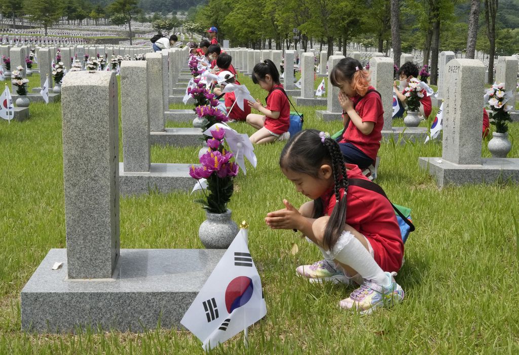 Murid-murid taman kanak-kanak sedang berdoa di depan nisan tentara yang tewas selama Perang Korea 1950-1953 di Pemakaman Nasional di Seoul, Korea Selatan, Senin, 5 Juni 2023. 