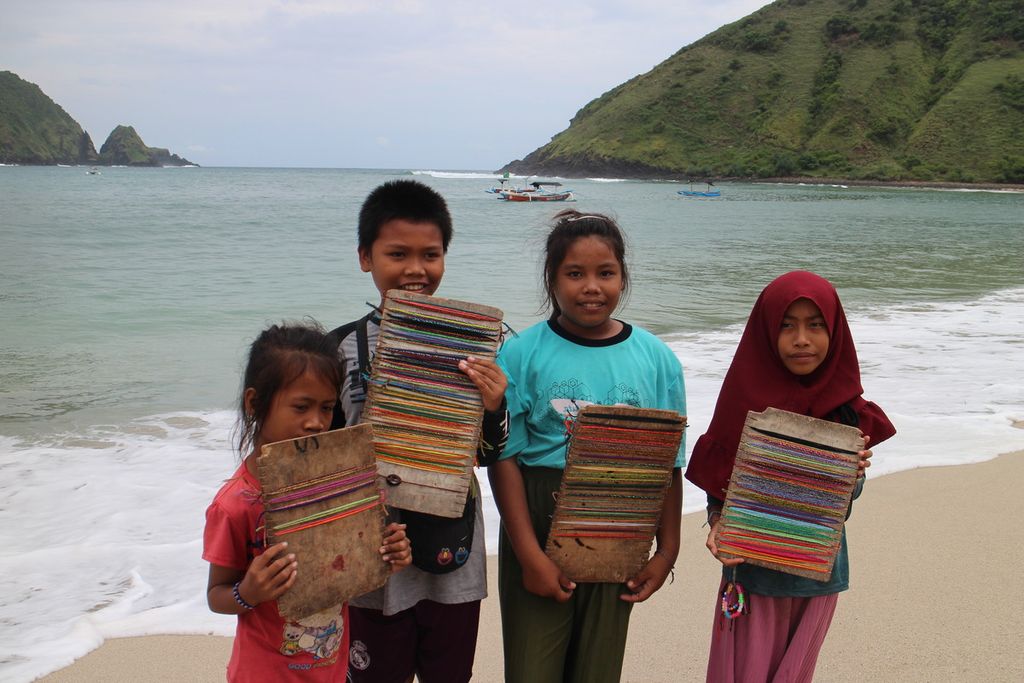 Anak-anak menjajakan cendera mata gelang di Pantai Mawun, Desa Tumpak, Kecamatan Punjut, Kabupaten Lombok Tengah, Jumat (4/3/2022).