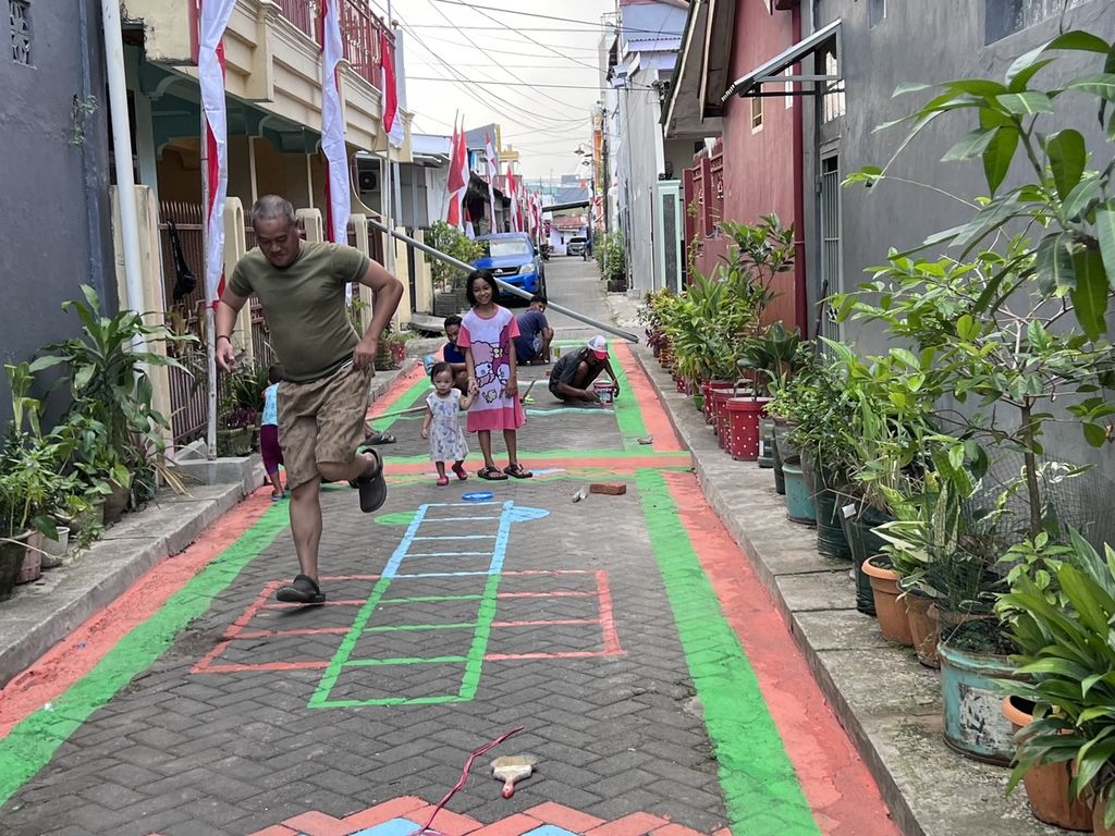 Seorang ayah dan anaknya bermain engklek (dende) di salah satu lorong wisata di Kelurahan Mappala, Kecamatan Rappocini, Makassar, Minggu (14/8/2022).